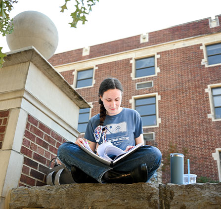 Photo of a student with a book. Link to Closely Held Business Stock.